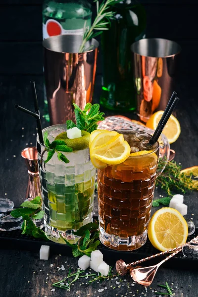 Long Island and Mojito Alcoholic Cocktails. On a black wooden background.