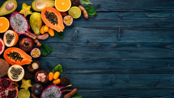 Tropical fruits, papaya, Dragon Fruit, rambutan, tamarind, cactus fruit, avocado, granadilla, carambola, kumquat, mango, mangosteen, passionfruit, coconut. On a wooden background.