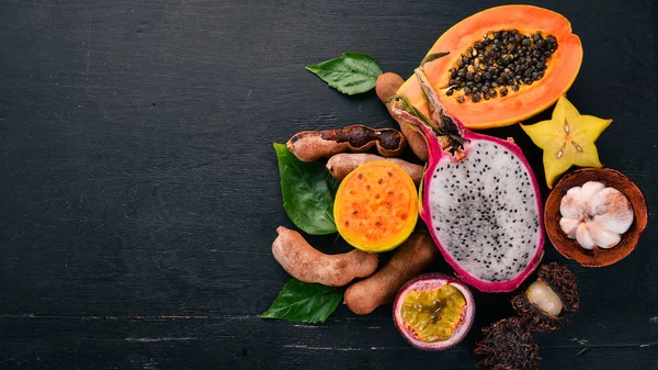 Papaya, Dragon Fruit, Cactus Fruit. Fresh Tropical Fruits. On a wooden background. Top view. Copy space.