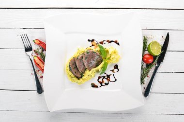 Dana dil bir tabak patates püresi ile haşlanmış. Ahşap bir arka plan üzerinde. Üstten Görünüm. Kopya alanı.