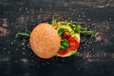 Burger, avokado sandviç, kiraz domates ve marul yaprakları. Ahşap bir arka plan üzerinde. Üstten Görünüm. Kopya alanı.