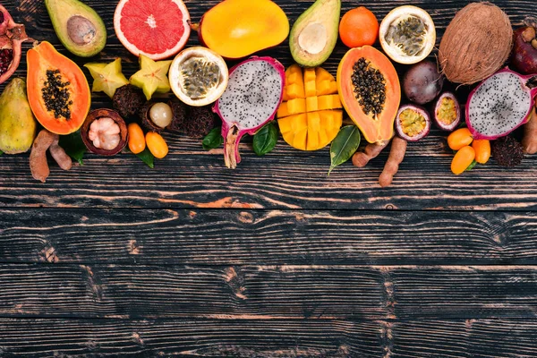 Tropikal meyveler, papaya, Dragon meyve, rambutan, demirhindi, kaktüs meyve, avokado, granadilla, carambola, Kamkat, mango, mangosten, Çarkıfelek, Hindistan cevizi. Ahşap bir arka plan üzerinde.