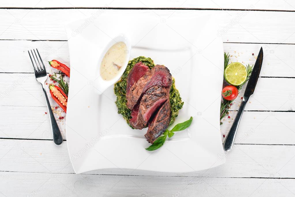 Peper Steak of veal with spinach. On a wooden background. Top view. Copy space.