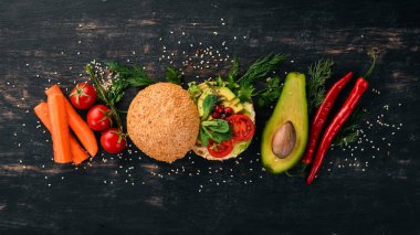 Burger, avokado sandviç, kiraz domates ve marul yaprakları. Ahşap bir arka plan üzerinde. Üstten Görünüm. Kopya alanı.