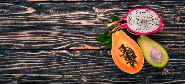 Papaya, Dragon Fruit, Cactus Fruit. Fresh Tropical Fruits. On a wooden background. Top view. Copy space.