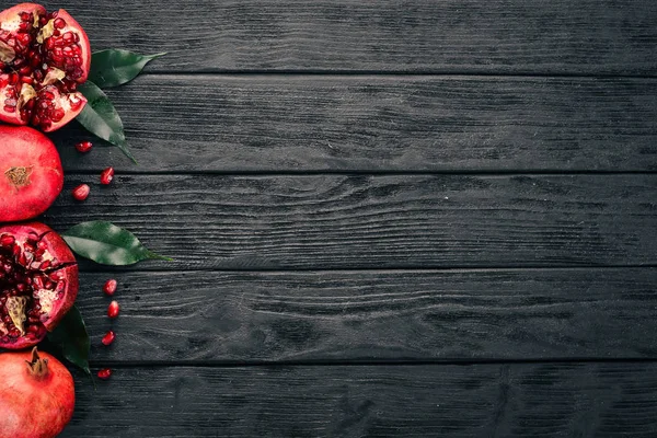 Fresh pomegranate. On a black wooden background. Top view. Copy space.