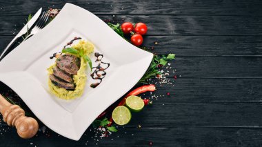 Dana dil bir tabak patates püresi ile haşlanmış. Ahşap bir arka plan üzerinde. Üstten Görünüm. Kopya alanı.