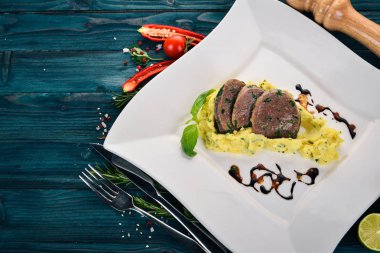 Dana dil bir tabak patates püresi ile haşlanmış. Ahşap bir arka plan üzerinde. Üstten Görünüm. Kopya alanı.