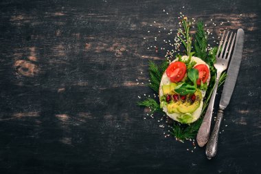 Burger, avokado sandviç, kiraz domates ve marul yaprakları. Ahşap bir arka plan üzerinde. Üstten Görünüm. Kopya alanı.