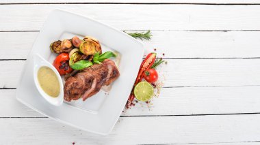 Domuz eti biftek bir plaka üzerinde ızgara sebzeler ile. Ahşap bir arka plan üzerinde. Üstten Görünüm. Kopya alanı.