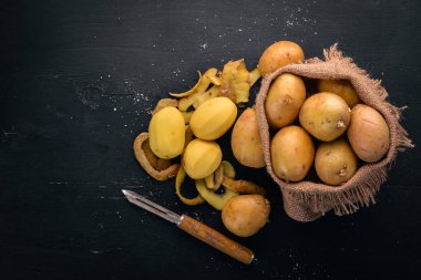 Çiğ patates siyah ahşap zemin. Yemek. Metin için özgür yer. Üstten Görünüm.