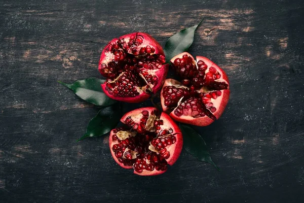 Fresh pomegranate. On a black wooden background. Top view. Copy space.