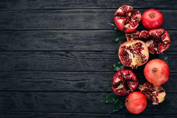 Fresh pomegranate. On a black wooden background. Top view. Copy space.
