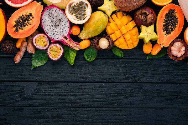 Тропические фрукты, папайя, фрукты дракона, рамбутан, тамаринда, фрукты кактуса, авокадо, гранадилья, карамбола, кумкват, манго, мангостин, пассионфрукт, кокос. На деревянном фоне
.