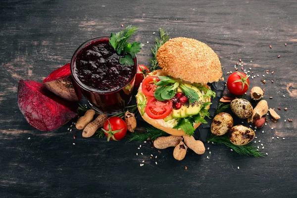 Breakfast. Beetroot juice and avocado burger and vegetables. On a wooden background. Top view. Copy space.