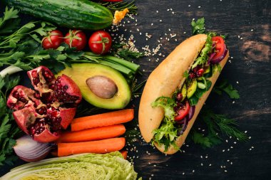 Burger, avokado sandviç, kiraz domates ve marul yaprakları. Ahşap bir arka plan üzerinde. Üstten Görünüm. Kopya alanı.