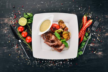 Domuz eti biftek bir plaka üzerinde ızgara sebzeler ile. Ahşap bir arka plan üzerinde. Üstten Görünüm. Kopya alanı.