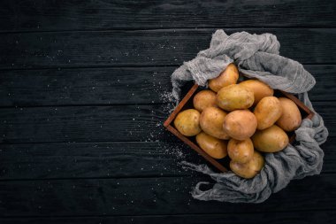 Çiğ patates siyah ahşap zemin. Yemek. Metin için özgür yer. Üstten Görünüm.