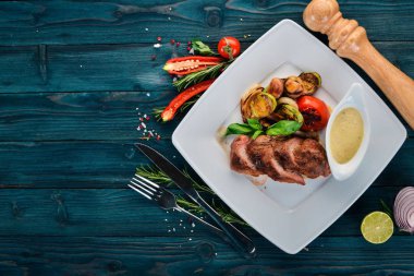 Domuz eti biftek bir plaka üzerinde ızgara sebzeler ile. Ahşap bir arka plan üzerinde. Üstten Görünüm. Kopya alanı.