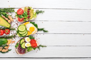 Burger ayarla, sandviç. Bıldırcın yumurta, salatalık ve Mısır, salam ve deniz ürünleri ile. Ahşap bir arka plan üzerinde. Üstten Görünüm. Kopya alanı.