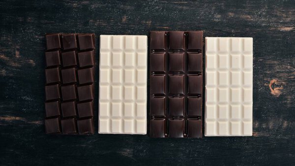 Dark and milky white chocolate on a wooden table. Top view. Copy space for text.