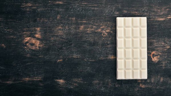 White milk chocolate on a wooden table. Top view. Copy space for text.