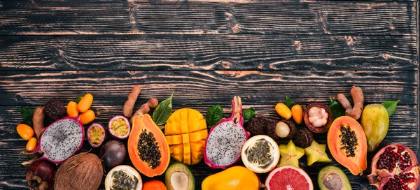 Tropical fruits, papaya, Dragon Fruit, rambutan, tamarind, cactus fruit, avocado, granadilla, carambola, kumquat, mango, mangosteen, passionfruit, coconut. On a wooden background.