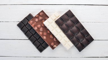 Karanlık ve sütlü Beyaz ahşap bir masaya çikolata. Üstten Görünüm. Metin için yer kopyalayın.