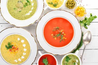 Sıcak, renkli sebze çorba kümesi. Brokoli çorbası, Mısır, domates çorbası. Sağlıklı gıda. Beyaz ahşap zemin üzerinde. Kopya alanı.