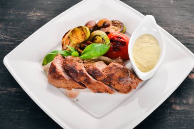 Domuz eti biftek bir plaka üzerinde ızgara sebzeler ile. Ahşap bir arka plan üzerinde. Üstten Görünüm. Kopya alanı.