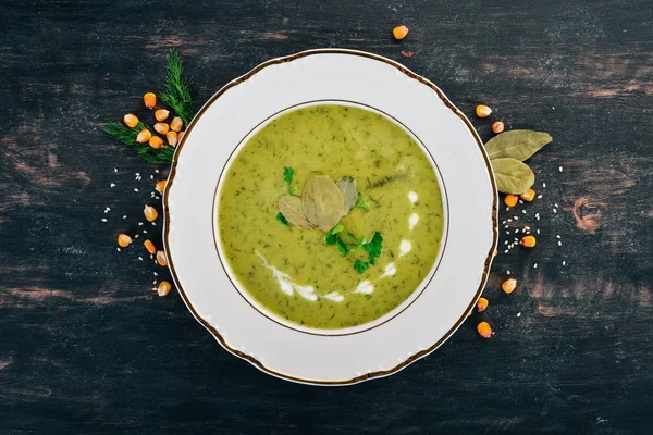 Soup with broccoli and peas and vegetables in a bowl. Healthy food. On a black wooden background. Top view. Copy space for your text.