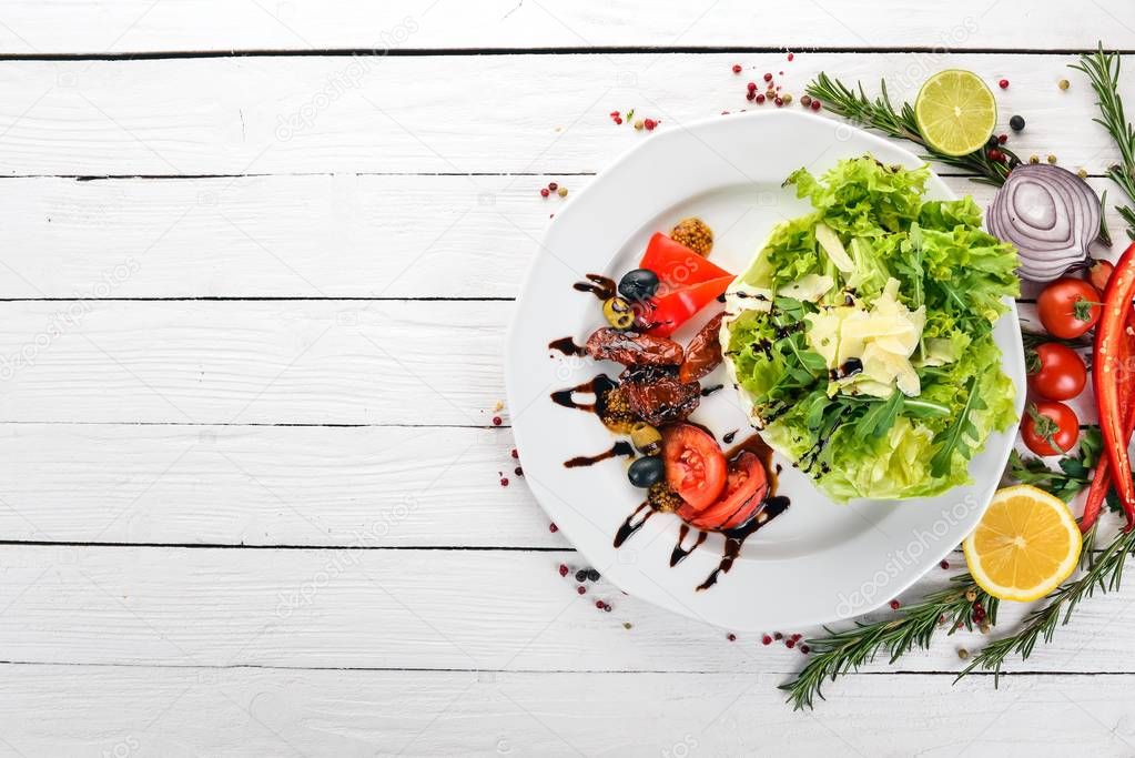 Salad with tomatoes, arugula and smoked tomatoes. On a wooden background. Top view. Copy space.