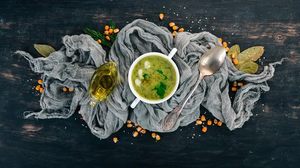 Soup with broccoli and peas and vegetables in a bowl. Healthy food. On a black wooden background. Top view. Copy space for your text.