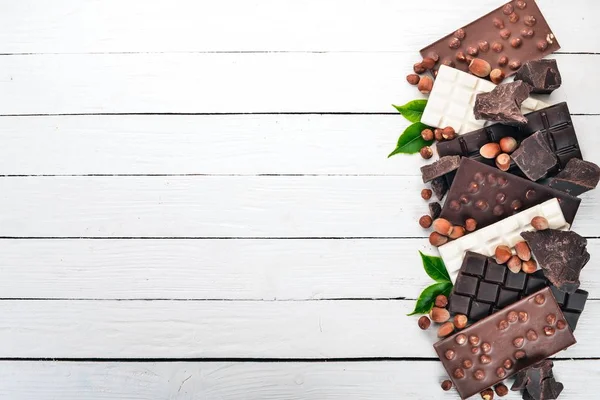 ミルク チョコレート ブラック チョコレート ヘーゼル ナッツのセット 白い木製の背景 コピーのテキストのための領域 — ストック写真