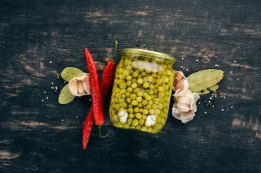 Turşu yeşil bezelye. Siyah ahşap arka plan üzerinde. Üstten Görünüm. Metniniz için kopya alanı.