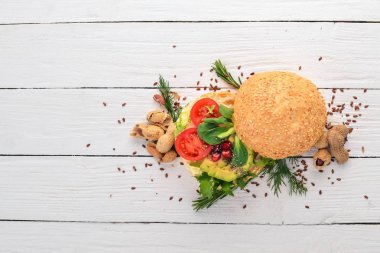 Burger, avokado sandviç, kiraz domates ve marul yaprakları. Ahşap bir arka plan üzerinde. Üstten Görünüm. Kopya alanı.