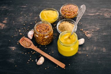 Ürün yelpazesine hardal sosları. Baharat siyah bir ahşap zemin üzerine. Üstten Görünüm. Metniniz için kopya alanı.