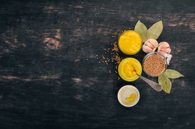 Ürün yelpazesine hardal sosları. Baharat siyah bir ahşap zemin üzerine. Üstten Görünüm. Metniniz için kopya alanı.