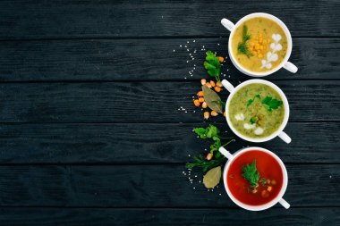 Sıcak, renkli sebze çorba kümesi. Brokoli çorbası, Mısır, domates çorbası. Sağlıklı gıda. Siyah ahşap arka plan üzerinde. Kopya alanı.