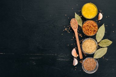 Ürün yelpazesine hardal sosları. Baharat siyah bir ahşap zemin üzerine. Üstten Görünüm. Metniniz için kopya alanı.