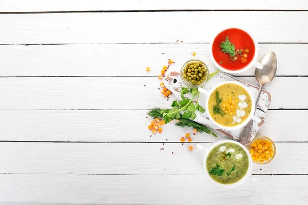 Set of hot, colored vegetable soups. Broccoli soup, corn, tomato soup. Healthy food. On a white wooden background. Copy space. — Stock Image Set Hot Colored Vegetable Soups Broccoli Soup Corn Tomato Soup Royalty Free Stock Images