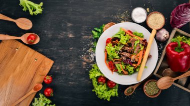 Dana eti ve mantar sebze salatası. Siyah ahşap arka plan üzerinde. Üstten Görünüm. Metniniz için kopya alanı.