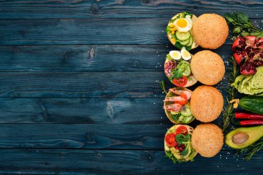 Burger ayarla, sandviç. Bıldırcın yumurta, salatalık ve Mısır, salam ve deniz ürünleri ile. Ahşap bir arka plan üzerinde. Üstten Görünüm. Kopya alanı.