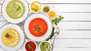 Sıcak, renkli sebze çorba kümesi. Brokoli çorbası, Mısır, domates çorbası. Sağlıklı gıda. Beyaz ahşap zemin üzerinde. Kopya alanı.