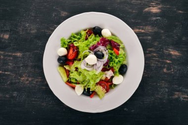Mozzarella ve taze sebze salatası. Siyah ahşap arka plan üzerinde. Üstten Görünüm. Metniniz için kopya alanı.
