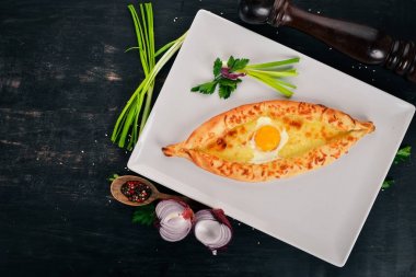 Khachapuri yumurta ve peynir ile. Gürcü mutfağı. Üstten Görünüm. Ahşap bir arka plan üzerinde. Kopya alanı.