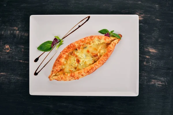 Khachapuri with cheese. Georgian cuisine. Top view. On a wooden background. Copy space.