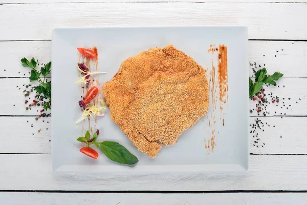 Schnitzel with sesame seeds and vegetables. Top view. On a wooden background. Copy space.