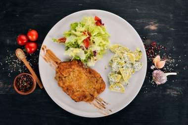 Fried şnitzel ile patates ve sebze. Üstten Görünüm. Ahşap bir arka plan üzerinde. Kopya alanı.
