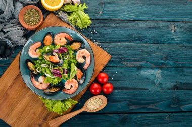 Bir tabak deniz ürünleri. Midye, mürekkep balığı, karides. Üstten Görünüm. Mavi ahşap arka plan üzerinde. Kopya alanı.